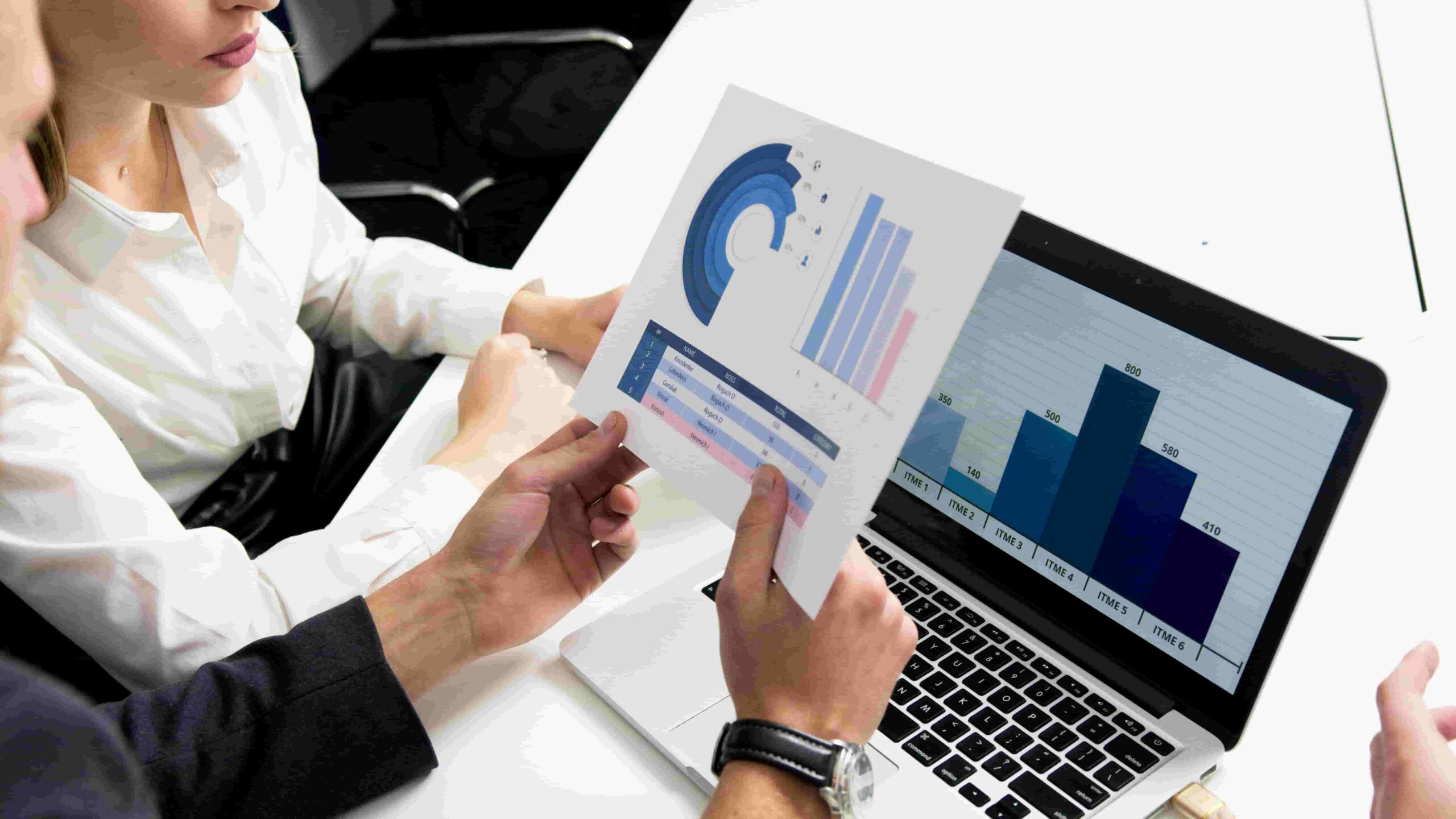 A group of people analyzing graphs displayed on a laptop screen, engaged in discussion and collaboration.